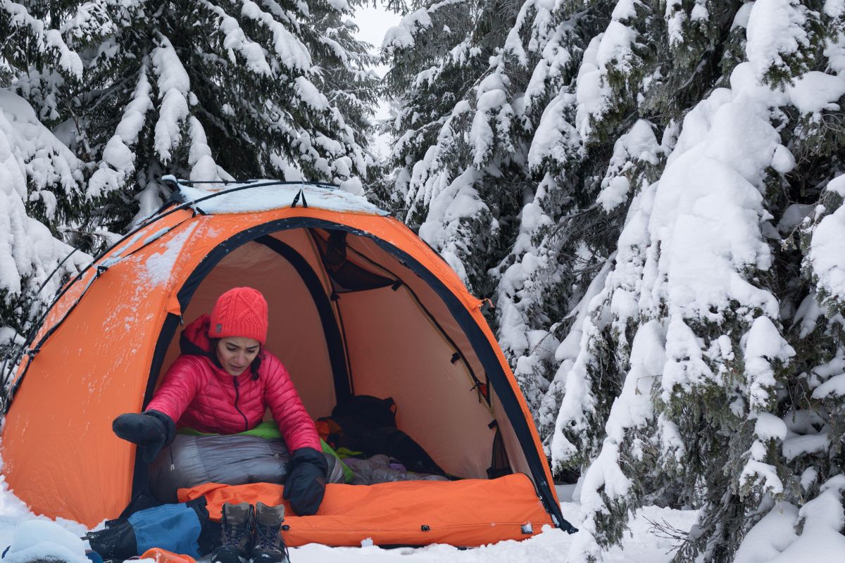 picture of a woman who knows how to stay warm winter camping in a tent